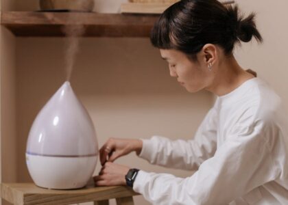 A person adjusting a humidifier, illustrating the function of humidifiers in contrast to dehumidifiers.