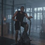 A man exercises on an air bike, illustrating the air bike's use in cardio workouts compared to elliptical bikes.
