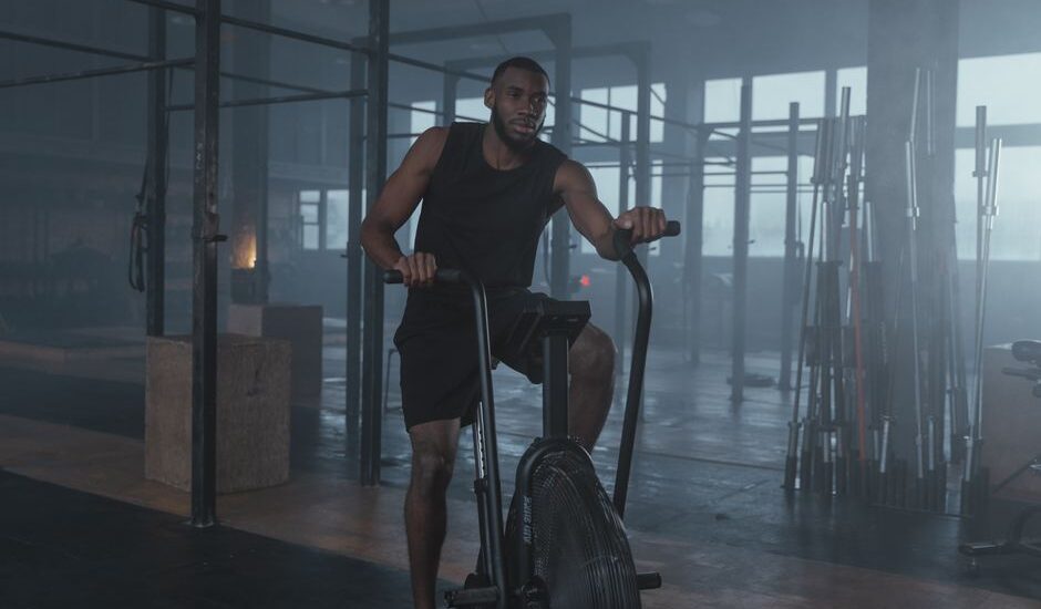 A man exercises on an air bike, illustrating the air bike's use in cardio workouts compared to elliptical bikes.