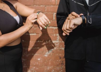 Two individuals adjusting fitness trackers on their wrists, relating to heart rate accuracy.
