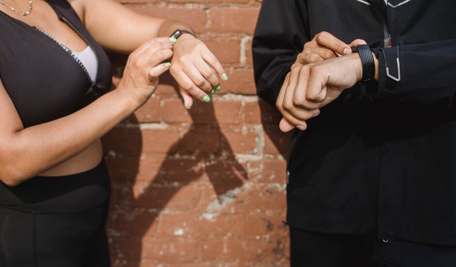 Two individuals adjusting fitness trackers on their wrists, relating to heart rate accuracy.
