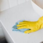 A person wearing yellow gloves wipes a surface while cleaning CPAP masks.