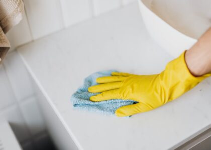 A person wearing yellow gloves wipes a surface while cleaning CPAP masks.