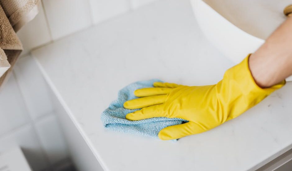 A person wearing yellow gloves wipes a surface while cleaning CPAP masks.