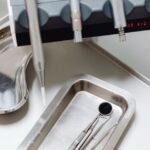 A dental mouth mirror and tools on a tray, illustrating cleaning methods.
