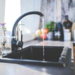 A kitchen sink with running water, illustrating the cleaning process for reusable ice packs.