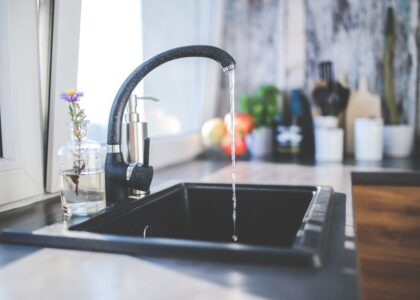 A kitchen sink with running water, illustrating the cleaning process for reusable ice packs.
