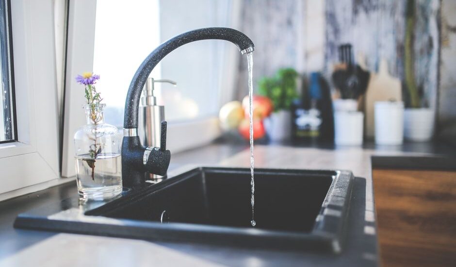 A kitchen sink with running water, illustrating the cleaning process for reusable ice packs.