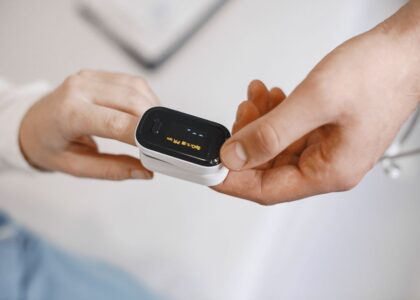 A person demonstrates how to disinfect a pulse oximeter while holding it.