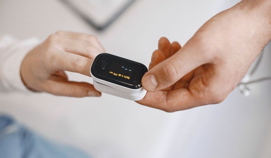 A person demonstrates how to disinfect a pulse oximeter while holding it.