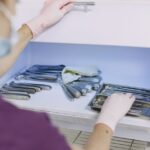 A person in gloves organizes sterilized dental tools in a fridge, illustrating home sterilization methods.