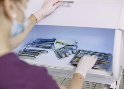 A person in gloves organizes sterilized dental tools in a fridge, illustrating home sterilization methods.