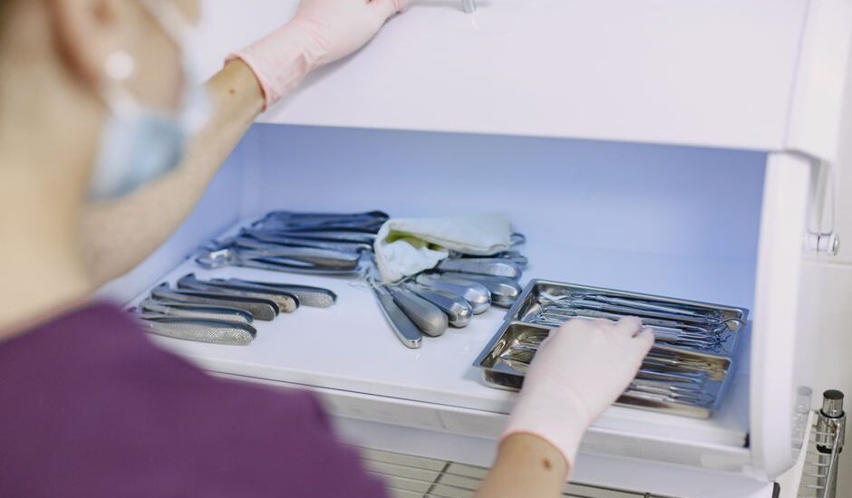 A person in gloves organizes sterilized dental tools in a fridge, illustrating home sterilization methods.