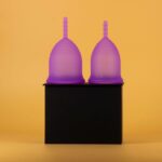 Two purple menstrual cups on a black surface, illustrating sterilization methods at home.
