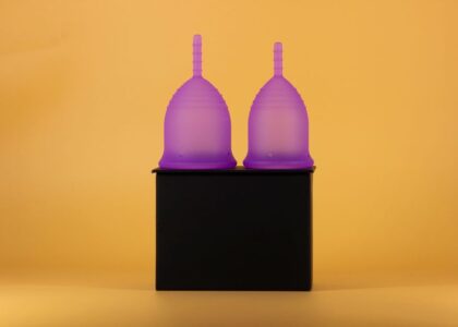 Two purple menstrual cups on a black surface, illustrating sterilization methods at home.