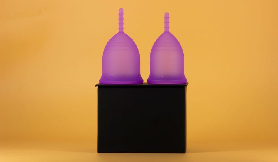 Two purple menstrual cups on a black surface, illustrating sterilization methods at home.