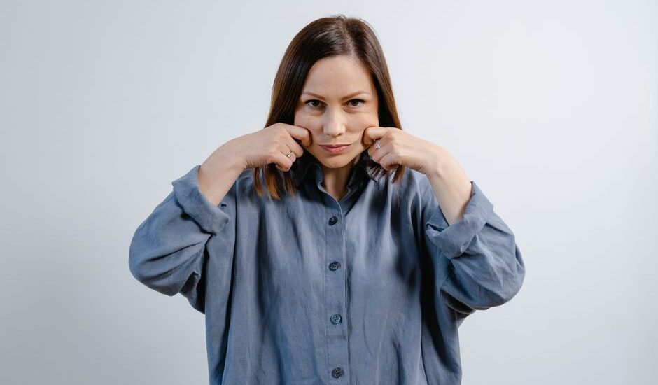 A woman demonstrating jaw exercises, relevant to using a jaw exerciser.
