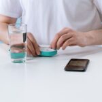 A person demonstrates a pill splitter while holding a pill and glass of water, related to pill splitter reviews.