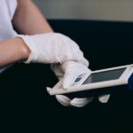 A person in gloves operates a portable mini EMS device, relevant for travel relief.