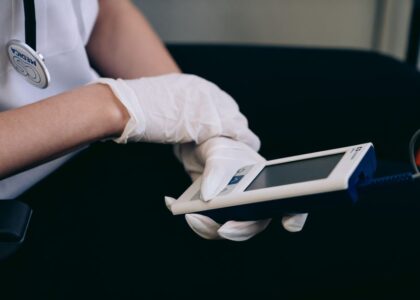 A person in gloves operates a portable mini EMS device, relevant for travel relief.