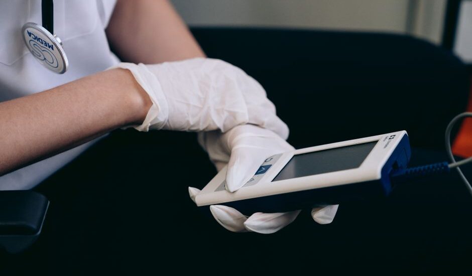 A person in gloves operates a portable mini EMS device, relevant for travel relief.