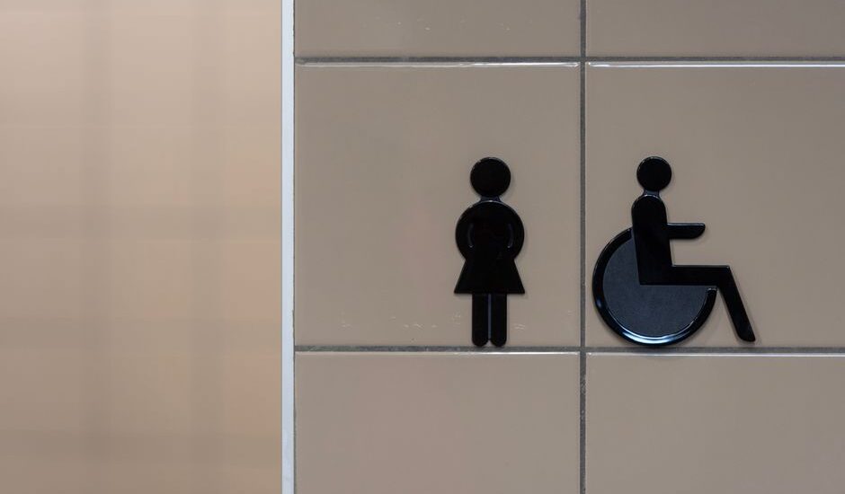 Bathroom signage indicating facilities for women and wheelchair users, relevant for adjustable shower chair discussions.