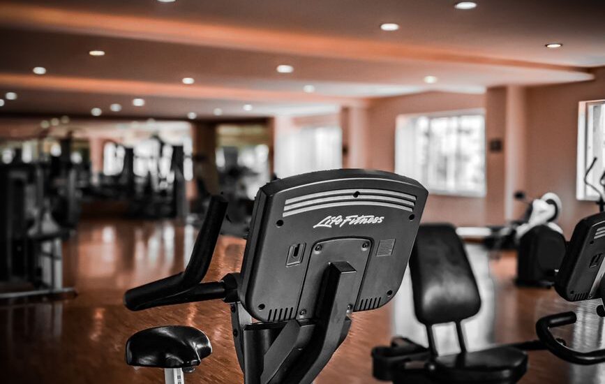 Image showing an upright bike and a recumbent bike in a gym, illustrating differences between bike types.