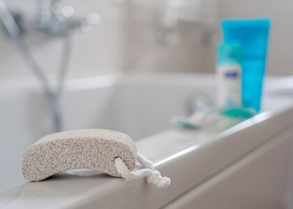 A pumice stone rests on the edge of a bathtub, relating to callus treatment.