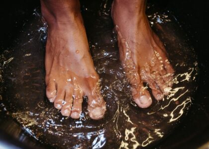 Feet soaking in water, illustrating preparation for using an electric callus remover or pumice stone.