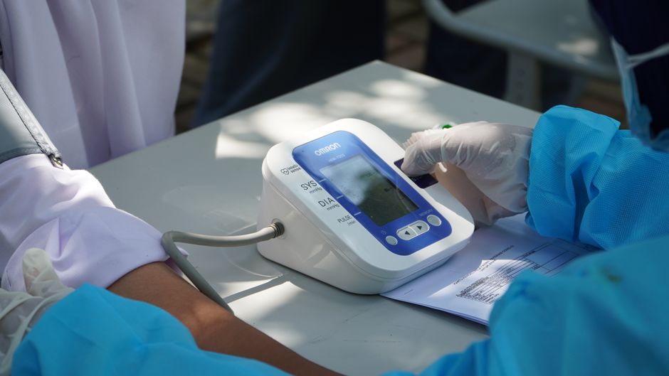 A person calibrating a digital blood pressure cuff on a table, relevant to blood pressure measurement.