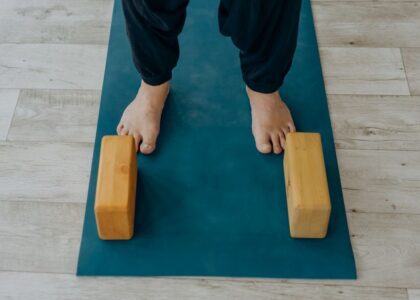 A person stands on a yoga mat with wooden blocks, illustrating how to disinfect yoga blocks.