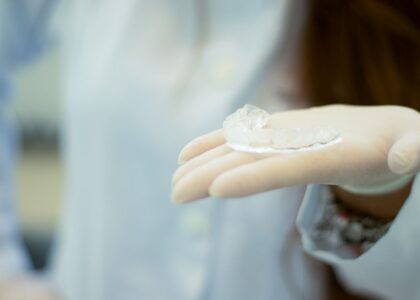 A hand wearing a glove holds a sleep apnea mouthpiece, relevant to sleep apnea solutions.