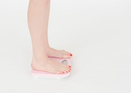 A person stands on a smart bathroom scale, illustrating its use with iPhone syncing.